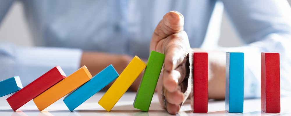 Businesswoman Stopping Dominoes On Desk